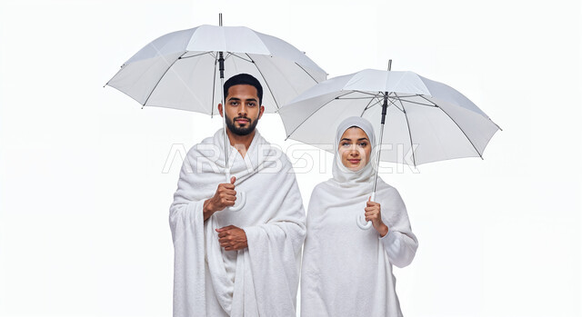 التظلل من اشعة الشمس باستخدام المظلة، مفهوم أركان الإسلام وأداء الفرائض الدينية، بورتريه مقرب لشاب حاج خليجي عربي سعودي يرتدي ثياب الإحرام يقف بجانب زوجته باستقامة بتعابير السرور، تأدية مناسك الحج والعمرة، العبادة والتقرب إلى الله، خلفية بيضاء