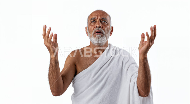 مفهوم أركان الإسلام وأداء الفرائض الدينية، رفع اليدين والدعاء بخشوع وتضرع، بورتريه مقرب لحاج كبير بالسن خليجي عربي سعودي يرتدي ثياب الإحرام يقوم بتأدية مناسك الحج والعمرة، العبادة والتقرب إلى الله، خلفية بيضاء