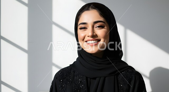 الاهتمام بالمظهر الخارجي، مفهوم الأنوثة والنعومة، الملامح العربية القوية، أزياء محجبات عصرية وأنيقة، صورة مقربة لشابة عربية خليجية سعودية ترتدي العباءة والحجاب بإيماءات البهجة والسرور