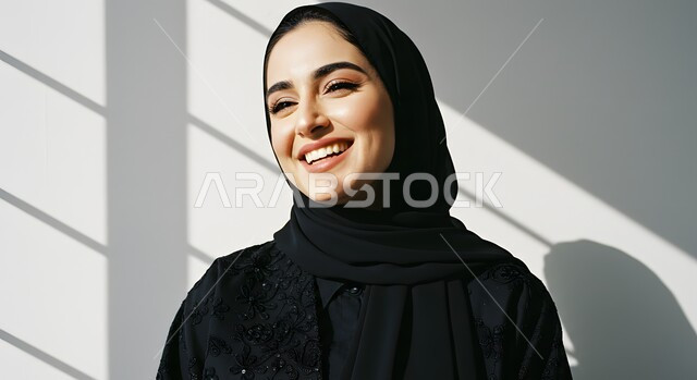 الاهتمام بالمظهر الخارجي، مفهوم الأنوثة والنعومة، الملامح العربية القوية، أزياء محجبات عصرية وأنيقة، صورة مقربة لشابة عربية خليجية سعودية ترتدي العباءة والحجاب بإيماءات البهجة والسرور