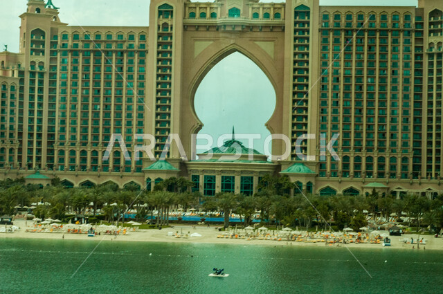 الاهتمام بزراعة اشجار النخيل والنباتات الخضراء، شاطئ البحر امام منتجع سياحي في مدينة دبي، مكان ومعلم مشهور في الامارات العربية المتحدة، الفن الهندسي المعماري على الطراز الحديث لفندق اتلانتس النخلة الشهير