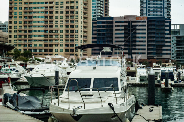 Towers and skyscrapers in the United Arab Emirates, the advanced architecture of commercial facilities, a famous coastal landmark and tourist spot, a yacht port and marine transportation during the day