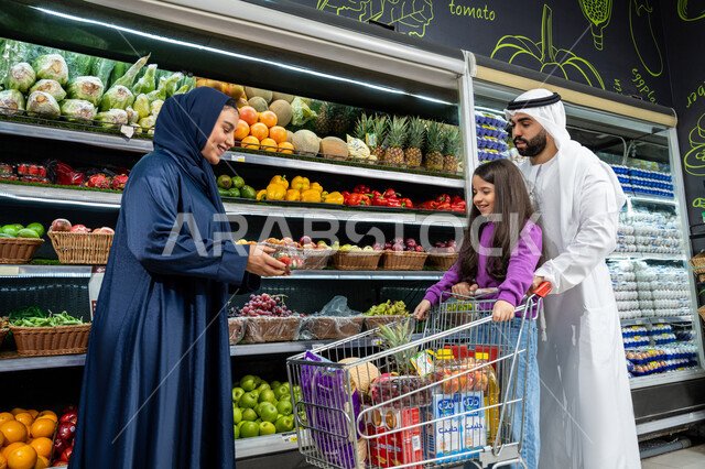ترابط وتعاون الاسره في التسوق، ام خليجيه تقوم بوضع علبه فراوله في سله التسوق،  الإستمتاع بالشراء والتبضع بِإيماءات السعاده و السرور، زوجان عربيان خليجيان اماراتيان يرتديان الزي التقليدي يقومان بالتسوق برفقة ابنتهم، محاصيل زراعيه وطنية اماراتية
