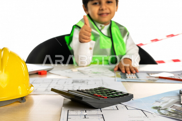 بورتريه لفتى عربي خليجي سعودي داخل مكتب هندسي ، إستخدام جهاز الحاسوب المحمول للبحث ، خوذة الوقاية ، أدوات ومعدات هندسية ، يرتدي سترة الحماية الخاصة بالعمل ، مهنة مستقبلية ، خلفية بيضاء ، مفهوم الهندسة المعمارية ، مهن ووظائف هندسية