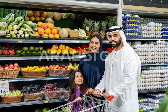 المواد الغذائية على الرفوف في المحلات والمراكز التجارية، التعاون في شراء السلع والمواد الغذائيه المختلفة في السوبرماركت، زوجان عربيان خليجيان اماراتيان يقومان بقضاء أوقات ممتعة بالتسوق واختيار اللوازم المنزليه برفقه ابنتهم، مساعدة وتعليم الأبناء الشراء