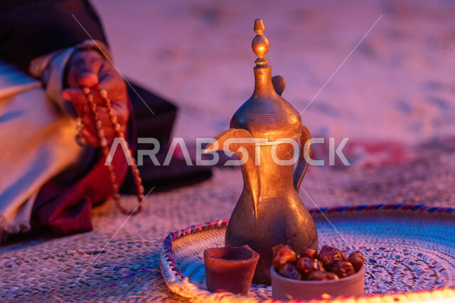 مفهوم الكرم وحسن الاستقبال، ذكرى تأسيس الدولة السعودية الاولى 22 فبراير، يوم بدينا 1727 م، الاحتفال بالمناسبات والأعياد الوطنية، صورة مقربة لرجل عربي خليجي سعودي يرتدي الأزياء التراثية يجلس بجانب دلة القهوة النحاسية، عادات وتقاليد موروثة