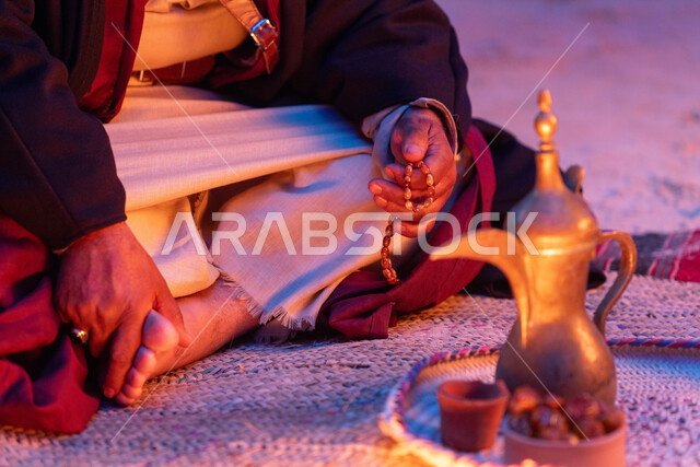 The concept of generosity and hospitality, the anniversary of the founding of the first Saudi state, February 22, the day of our beginnings in 1727 AD, celebrating national occasions and holidays, a close-up image of a Saudi Arabian Gulf man wearing traditional costumes sitting next to a copper coffee pot, inherited customs and traditions