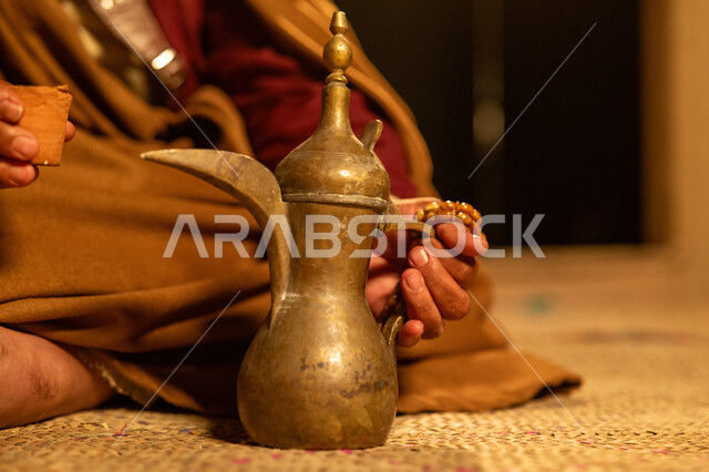  ذكرى تأسيس الدولة السعودية الاولى 22 فبراير، يوم بدينا 1727 م، الاحتفال بالمناسبات والأعياد الوطنية، صورة مقربة لرجل عربي خليجي سعودي يرتدي الأزياء التراثية يجلس بجانب دلة القهوة النحاسية، عادات وتقاليد موروثة، مفهوم الكرم وحسن الاستقبال
