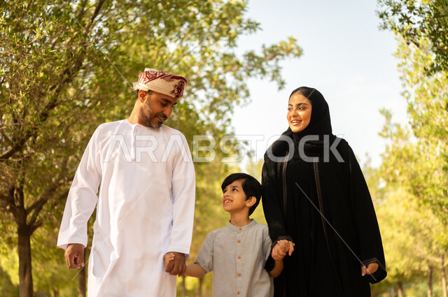 قضاء أوقات ممتعة مع الابناء, عائلة عربية خليجية عمانية تقوم المشي و التجول في الهواء الطلق و الطبيعة الخضراء, التنزه في إحدى حدائق سلطنة عمان, أنشطة عائلية ترفيهية, خلفية طبيعة