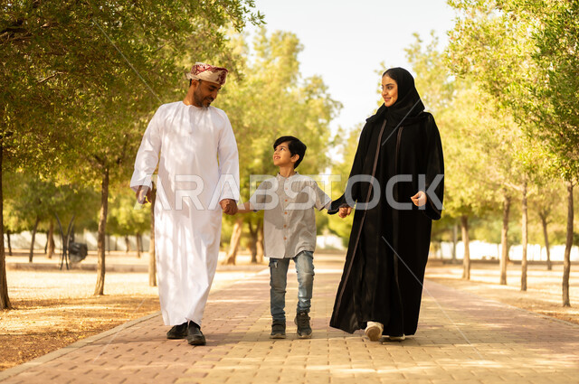 قضاء أوقات ممتعة مع الابناء, عائلة عربية خليجية عمانية تقوم المشي و التجول في الهواء الطلق و الطبيعة الخضراء, التنزه في إحدى حدائق سلطنة عمان, أنشطة عائلية ترفيهية, خلفية طبيعة