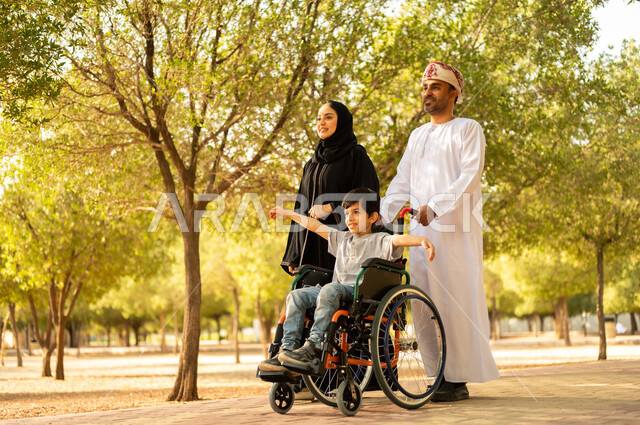شعور ذوي الهمم بالراحه والطمأنينه في بيئتهم, عائلة عربيه خليجيه عمانية برفقه ابنها في إحدى الحدائق للاستمتاع بالهواء الطلق، ولد عماني مقعد يجلس على كرسي متحرك في أحد المنتزهات، منح مرضى ذوي الإعاقة الحركية طاقة ايجابية