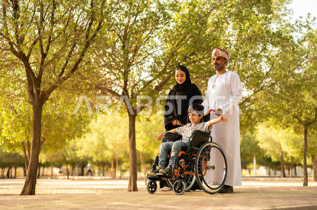 شعور ذوي الهمم بالراحه والطمأنينه في بيئتهم, عائلة عربيه خليجيه عمانية برفقه ابنها في إحدى الحدائق للاستمتاع بالهواء الطلق، ولد عماني مقعد يجلس على كرسي متحرك في أحد المنتزهات، منح مرضى ذوي الإعاقة الحركية طاقة ايجابية