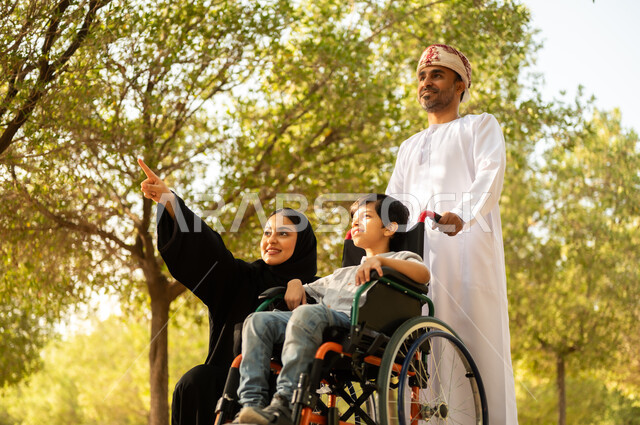 شعور ذوي الهمم بالراحه والطمأنينه في بيئتهم, عائلة عربيه خليجيه عمانية برفقه ابنها في إحدى الحدائق للاستمتاع بالهواء الطلق، ولد عماني مقعد يجلس على كرسي متحرك في أحد المنتزهات، منح مرضى ذوي الإعاقة الحركية طاقة ايجابية