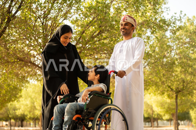 شعور ذوي الهمم بالراحه والطمأنينه في بيئتهم, عائلة عربيه خليجيه عمانية برفقه ابنها في إحدى الحدائق للاستمتاع بالهواء الطلق، ولد عماني مقعد يجلس على كرسي متحرك في أحد المنتزهات، منح مرضى ذوي الإعاقة الحركية طاقة ايجابية