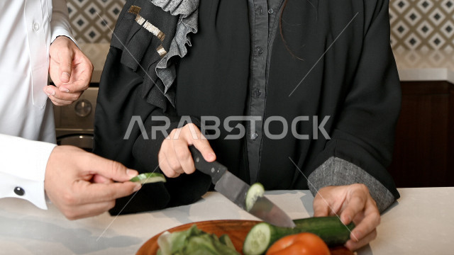 A Saudi Arabian Gulf couple help each other in preparing and preparing food, cutting vegetables to prepare delicious salads, preparing a healthy meal