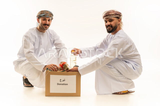 توفير المستلزمات الضرورية للفقراء، مبادرة إنسانية في سلطنة عمان، مفهوم المساعدة والتبرع، بورتريه لرجلين عربيين خليجيين عمانيين يرتديان الدشداشة والعمامة يقومان بتجهيز صناديق التبرعات، تقديم المعونة للمحتاجين، التقرب إلى الله بالعطاء والصدقة، خلفية بيضاء