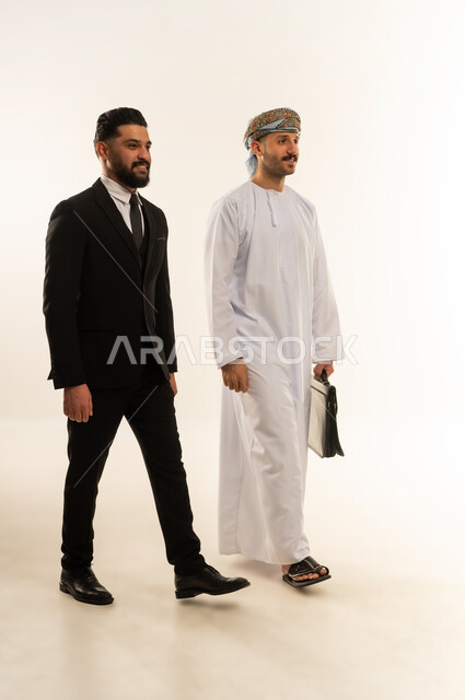 المشي والذهاب الى مكان ما، تبادل الخبرات والمعرفة بين البلاد, استضافة رجال الاعمال الاجانب في سلطنة عمان, بورتريه لرجل عربي خليجي عماني يرتدي الدشداشة والعمامة يتحاور مع سائح اجبني يرتدي البدلة الرسمية بتعابير السرور, صورة لكامل الجسم، خلفية بيضاء