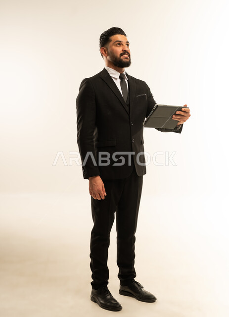 عقد اجتماع عمل، دمج الاجهزة الحديثة والتكنولوجيا في الحياة العملية، تصفح الانترنت وإنجاز المهام عن بعد، متابعه أخبار السوشال ميديا، بورتريه لرجل اعمال اجنبي يرتدي البدلة الرسمية يقوم باستخدام جهاز التابلت,  الجسم بالطول الكامل، خلفية بيضاء