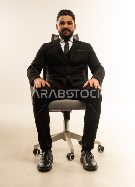 Self-confidence gestures, taking a selfie for official documents, the concept of elegance and masculinity, a portrait of a foreign businessman wearing a formal suit sitting on a chair looking at the camera with an expression of pleasure and happiness, concern for one's appearance, white background