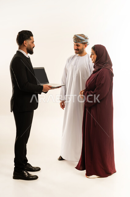 استخدام الحاسب المحمول، تبادل الخبرات بين البلاد، بورتريه لفريق عمل عربي خليجي عماني في اجتماع مع رجل اجنبي يرتدي البدلة الرسمية بتعابير السرور والسعادة، استضافة رجال الاعمال الاجانب في سلطنة عمان، الجسم بالطول الكامل، خلفية بيضاء