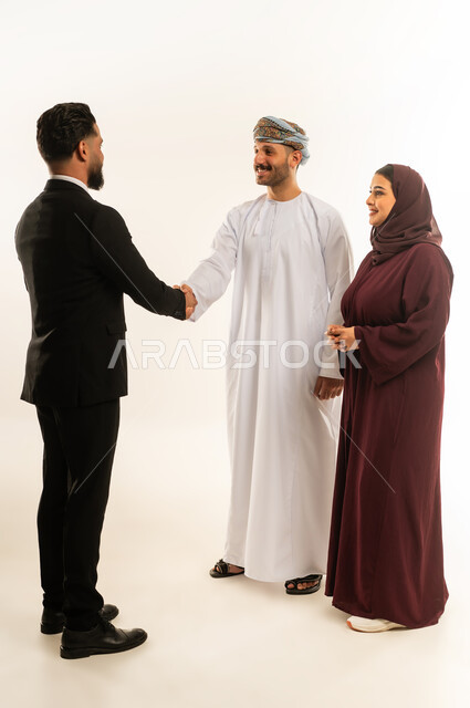 استخدام الحاسب المحمول، تبادل الخبرات بين البلاد، بورتريه لفريق عمل عربي خليجي عماني في اجتماع مع رجل اجنبي يرتدي البدلة الرسمية بتعابير السرور والسعادة، استضافة رجال الاعمال الاجانب في سلطنة عمان، الجسم بالطول الكامل، خلفية بيضاء