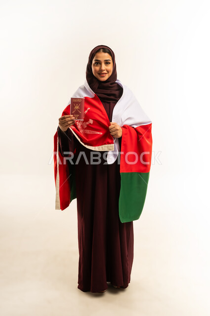 وثيقة سفر رسمية، إحياء ذكرى تأسيس الدولة 1775 م، حب الوطن والانتماء إليه، بورتريه من الخلف لإمرأة عربية خليجية عمانية ترتدي الحجاب والعباءة والعلم الوطني للبلاد تمسك جواز السفر، ذكرى اليوم الوطني العماني 18 نوفمبر، الجسم بالطول الكامل، خلفية بيضاء