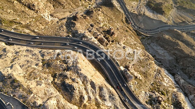 طريق إسفلتي ملتوي وعر وسط الجبال الصخرية، الطبيعة والبيئة الجبلية القاسية في مدينة الطائف، القمم والمرتفعات في المملكة العربية السعودية، حركة مرور السيارات في طريق عقبة الهدا، الطرق والشوارع المعبدة السريعة بين مكة والطايف, الاهتمام بتهيئة البنية التحتية