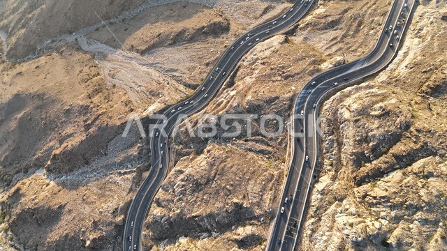 A winding, bumpy asphalt road in the middle of the rocky mountains, the harsh mountainous nature and environment of Taif, peaks and heights in the Kingdom of Saudi Arabia, car traffic on the Hada Pass Road, paved roads and highways between Mecca and Taif, attention to infrastructure development