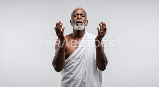 مفهوم أركان الإسلام وأداء الفرائض الدينية، رفع اليدين والدعاء بخشوع وتضرع، بورتريه مقرب لحاج خليجي عربي سعودي يرتدي ثياب الإحرام يقوم بتأدية مناسك الحج والعمرة، العبادة والتقرب إلى الله، خلفية بيضاء