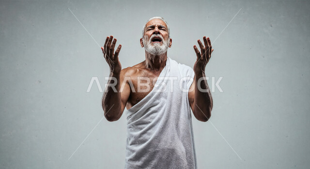 مفهوم أركان الإسلام وأداء الفرائض الدينية، رفع اليدين والدعاء بخشوع وتضرع، بورتريه مقرب لحاج خليجي عربي سعودي يرتدي ثياب الإحرام يقوم بتأدية مناسك الحج والعمرة، العبادة والتقرب إلى الله، خلفية بيضاء