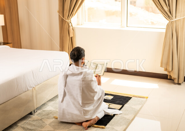 اداء الصلاة على وقتها، العبادة والتقرب إلى الله تعالى، صورة من الخلف لرجل يرتدي ثياب الاحرام يقرأ القرأن الكريم بتعابير الدعاء والتضرع, أداء مناسك الحج والعمرة، مكان ومعلم اسلامي ديني مقدس في المملكة العربية السعودية