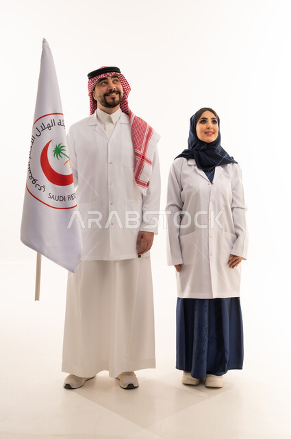 علم هيئة الهلال الأحمر السعودي، العمل في المجال الطبي، بورتريه لطبيبين سعوديين عربيين خليجيين يرتديان المعطف الأبيض يقفان باستقامه بتعابير الثقة بالنفس، الإسهام في الخدمات الإنسانية، تقديم الخدمة الطبية الإسعافية الطارئة، الجسم بالطول الكامل، خلفية بيضاء