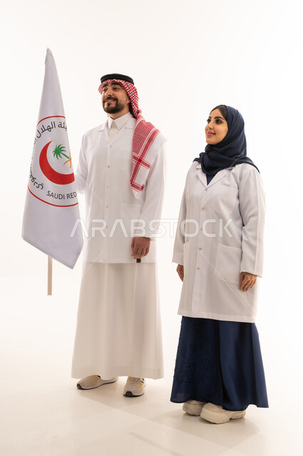 علم هيئة الهلال الأحمر السعودي، العمل في المجال الطبي، بورتريه لطبيبين سعوديين عربيين خليجيين يرتديان المعطف الأبيض يقفان باستقامه بتعابير الثقة بالنفس، الإسهام في الخدمات الإنسانية، تقديم الخدمة الطبية الإسعافية الطارئة، الجسم بالطول الكامل، خلفية بيضاء
