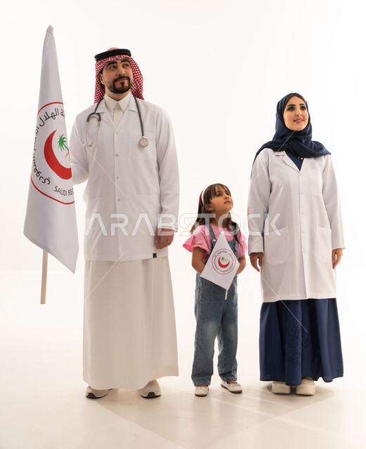 علم هيئة الهلال الأحمر السعودي، العمل في المجال الطبي، بورتريه لطبيبين سعوديين عربيين خليجيين يرتديان المعطف الأبيض يقفان بجانب فتاة تمسك بيدها شعار الهيئة، الإسهام في الخدمات الإنسانية، تقديم الخدمة الطبية الإسعافية الطارئة، الجسم بالطول الكامل، خلفية بيضاء