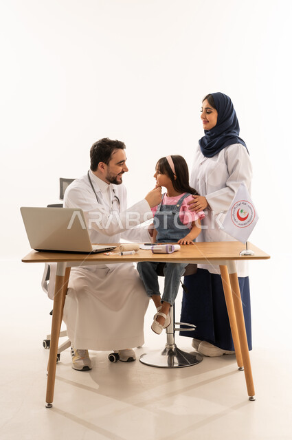 المساهمة في الخدمات الطبية الإسعافية الطارئة، دمج التكنولوجيا والتقنية في المجال الطبي والصحي، العمل في هيئة الهلال الأحمر السعودي، بورتريه لطبيبين سعوديين عربيين خليجيين يرتديان المعطف الأبيض يقومان فتاة، العمل على الحاسوب المحمول، خلفية بيضاء