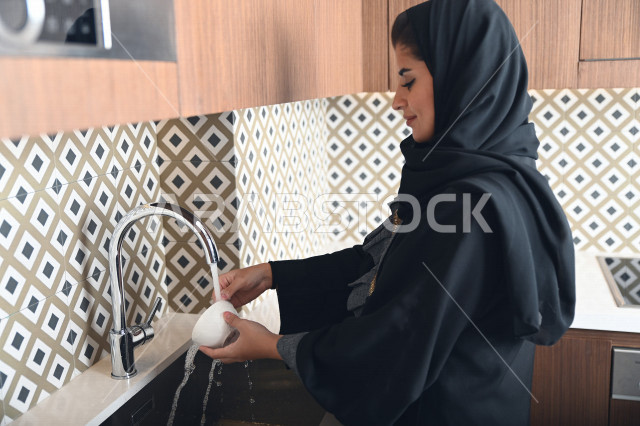A Saudi Arabian Gulf woman who washes the dishes, finishes cleaning the kitchen, takes care of the cleanliness of the house, and completes daily household tasks