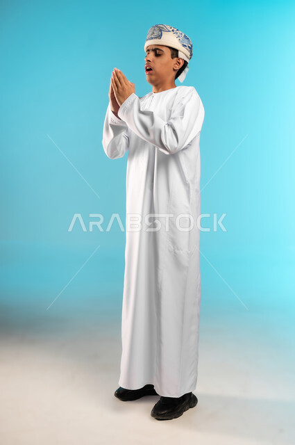 العطاس والكحه وأعراض الرشح، ضرورة أخذ العلاج المناسب، الإرهاق والتعب والحاجة للراحة، الإصابة بالزكام والانفلونزا، بورتريه لولد عربي خليجي عماني يرتدي الدشداشة والكمه العمانية يمسك المنديل الورقي بيده لمنع انتشار العدوى، الجسم بالطول الكامل، خلفية زرقاء .
