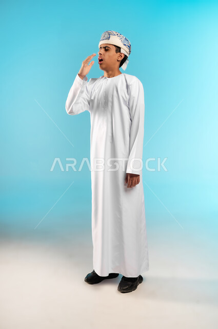 Fatigue, exhaustion and need for rest, sneezing, coughing and cold symptoms, the need to take appropriate treatment, catching a cold and the flu, portrait of an Arab Gulf Omani boy wearing a dishdasha and an Omani cuff holding a tissue in his hand to prevent the spread of infection, full body, blue background.