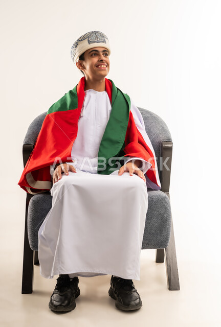 الفرح والسرور لفوز المنتخب الوطني ، ايماءات الحماس والتشجيع، تشجيع الفريق العماني، بورتريه لولد عربي خليجي عماني يرتدي الدشداشة والكمة ووشاح ينظر الى الاعلى وتظهر عليه تعابير السعادة, صورة الجسم بالطول الكامل, خلفية بيضاء .