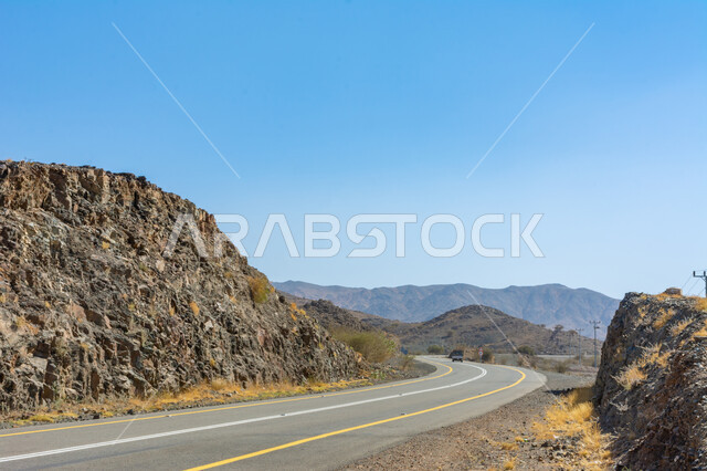 Paved road between the mountain peaks and heights in the Kingdom of Saudi Arabia, asphalt roads and streets in natural desert areas, facilitating the movement of citizens traveling, preparing the infrastructure