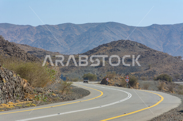 Paved road between the mountain peaks and heights in the Kingdom of Saudi Arabia, asphalt roads and streets in natural desert areas, facilitating the movement of citizens traveling, preparing the infrastructure