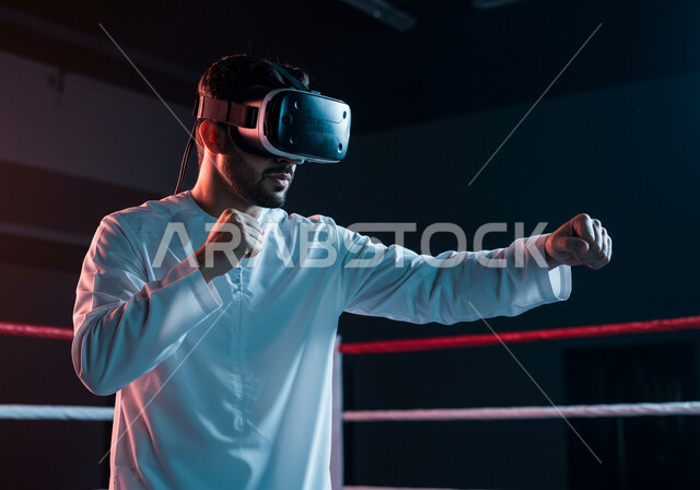 تفريغ الطاقة السلبية، ممارسة رياضة الدفاع عن النفس بتقنيات تكنولوجية، التدرب على الحركات القتالية من خلال ألعاب الفيديو، شاب عربي خليجي سعودي يرتدي نظارات الواقع الافتراضي بإيماءات الملاكمة والمصارعة