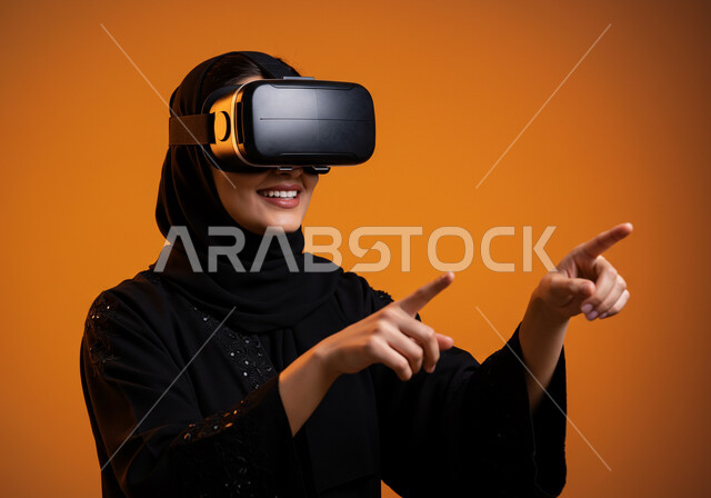 التكنولوجيا الحديثة واستخدام الأجهزة المتطورة، المتعة والتسلية بمحاكاة العالم الخيالي، الاندماج والتفاعل مع الواقع الافتراضي, بورتريه مقرب لامرأة عربية خليجية سعودية محجبة ترتدي نظارة في آر ثلاثية الأبعاد بايماءات التفاعل, خلفية برتقالية