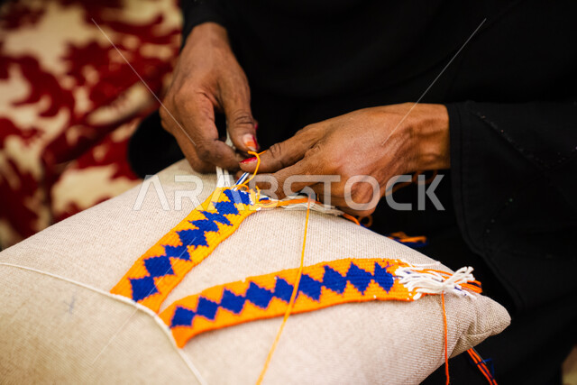 Heritage and authenticity in the Kingdom of Saudi Arabia, historical handicrafts, ancient works and industries, the use of dried palm leaves in basket making, local Saudi national products, traditional folk professions, a close-up of the hand of a Saudi Arabian Gulf woman weaving palm fronds