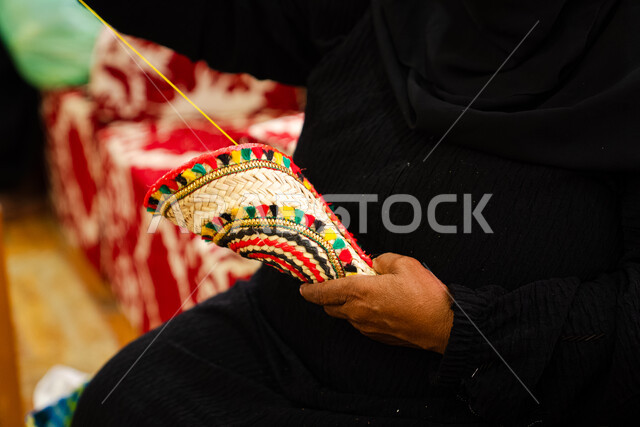 التراث والأصالة في دولة المملكة العربية السعودية, حرف يدوية تاريخية, أعمال وصناعات قديمة, استخدام أوراق النخيل المجففة في صناعة السلل, منتجات محلية وطنية سعودية, مهن شعبية تقليدية, صورة مقربة ليد إمرأة عربية خليجية سعودية تقوم بجدل سعائف الخوص