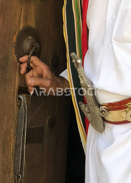  ارتداء أزياء المنطقة الشرقية، يوم بدينا 1727 م، صورة مقربة لشاب عربي خليجي سعودي يقوم بارتداء المحزم  بتعابير الثقة بالنفس، التباهي والفخر بإنجازات الوطن، ذكرى تأسيس الدولة السعودية الأولى في 22 فبراير