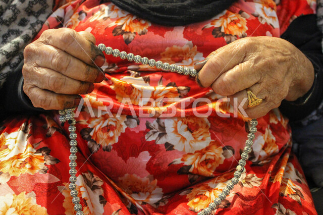 مفهوم التسبيح والتهليل، الاجتهاد في العبادة والتقرب إلى رب العالمين, صورة مقربة لأيدي إمرأة عربية خليجية سعودية ترتدي الزي التقليدي الشعبي تمسك بيدها سبحة, الإكثار من ذكر الله تعالى من خلال الاستغفار والدعاء، الالتزام بالأذكار اليومية