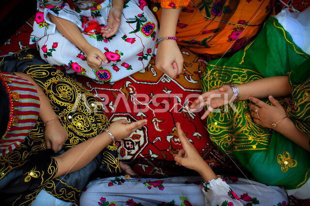 ألعاب متوارثة من الأجداد عبر الأجيال، قضاء وقت ممتع مع الاخوة، صورة علوية عامودية لعائلة عربية خليجية سعودية تلعب بألعاب يدوية بسيطة، التسلية والترفيه في الحياة البدوية