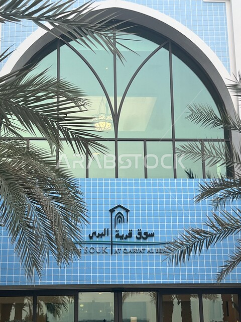 سوق قرية البري في امارة ابو ظبي في النهار، الفن الهندسي المعماري لمراكز التسوق المولات التجارية في الامارات العربية المتحدو، لافتة على الواجهه الزجاجية الكبيرة