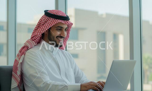 Managing and completing tasks using a modern and advanced technical device, a smiling Saudi Arabian Gulf man wearing a traditional shemagh and thobe working on a laptop at the company headquarters, gestures and expressions of pleasure and happiness, Saudi office jobs and professions